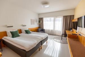 a hotel room with a large bed and a television at Hotel Waltikka in Valkeakoski