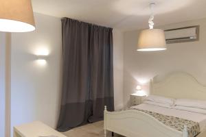 a bedroom with a white bed and a gray curtain at AH Premium Baia dei Faraglioni in Mattinata