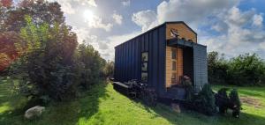 a black tiny house in a field with a bike at TinyEscape ca 1 Std von Hamburg entfernt in Delve