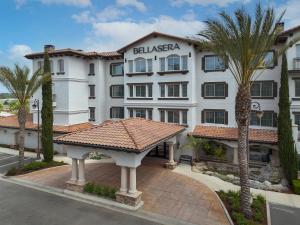 佩索罗伯斯Bellasera Hotel & Suites Paso Robles, Tapestry by Hilton的一座白色的大建筑,前面有棕榈树