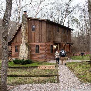 a group of people walking towards a log cabin at Sycamore - by The Chalets in South Bloomingville