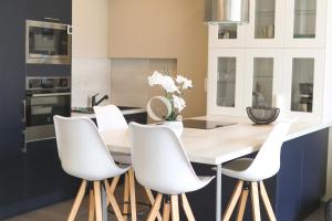 a kitchen with white chairs and a wooden table at GC - L'Entre Deux Caps in Wissant