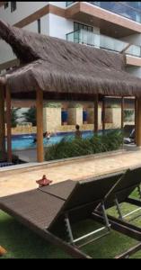 a pavilion with a grass roof and a pool at Complete beach house! in Cabedelo