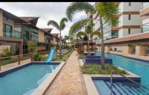 a pool at a resort with a slide and palm trees at Complete beach house! in Cabedelo