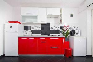 cocina con armarios rojos y nevera blanca en Apartment Mimice 4, en Mimice