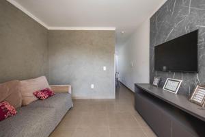 Una sala de estar con un sofá y un televisor de pantalla plana. en Completa casa apenas 700m da praia, en Itajubá