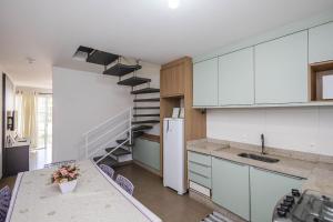 una cocina con armarios blancos y una escalera de caracol en Completa casa apenas 700m da praia, en Itajubá