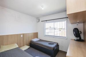 Una pequeña habitación con dos camas y una ventana. en Completa casa apenas 700m da praia, en Itajubá