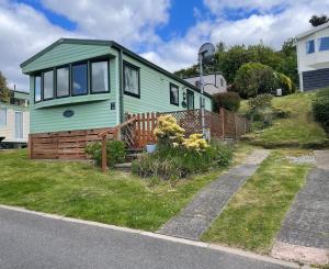 a green tiny house on the side of a street at Grannys Vintage Coastal Caravan in Kippford