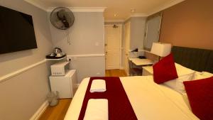 a bedroom with a bed with red pillows on it at Classic Hyde Park Hotel in London