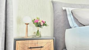 a table with a vase of flowers on it next to a bed at New Istrian Experience by Istrian apartments Koper in Koper