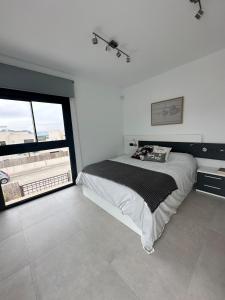 a white bedroom with a bed and a large window at Villa dans un magnifique golf in Algorfa