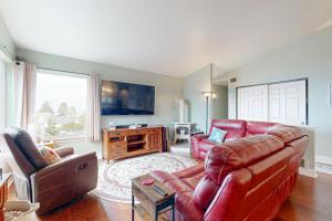 a living room with red leather furniture and a flat screen tv at Salty Sunsets in Depoe Bay