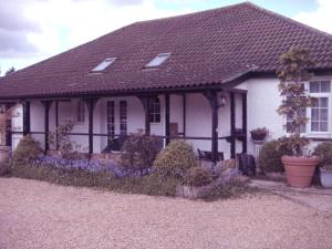 een wit huis met een zwart dak en een aantal planten bij Bluebell Cottage in Staines