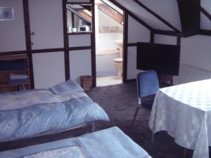 a bedroom with a bed and a table and a television at Bluebell Cottage in Staines