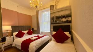 a bedroom with two beds with red pillows at Classic Hyde Park Hotel in London