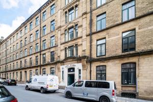ブラッドフォードにあるModern 2 Bedroom Apartment in Central Bradfordの大きなレンガ造りの建物の前に駐車した2台のバン