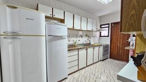 una cucina con elettrodomestici bianchi e mobili bianchi di Retiro dos Sonhos – Piscina, Jacuzzi e Sauna na Montanha a Teresópolis