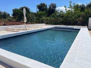 a swimming pool with two lounge chairs and a swimming pool at Il Trullino in Ostuni