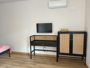 a black dresser with a television on a wall at SasApartamenty in Milanówek