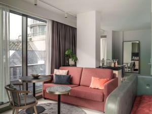 a living room with a pink couch and a large window at Hotel Norge by Scandic in Bergen