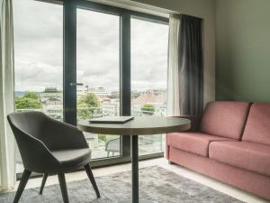 a living room with a table and a couch and a window at Hotel Norge by Scandic in Bergen