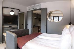 a bedroom with a large white bed and a mirror at Hotel Norge by Scandic in Bergen