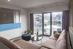 a living room with a couch and a large window at Hotel Norge by Scandic in Bergen
