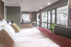a bedroom with a large bed with a large window at Hotel Norge by Scandic in Bergen