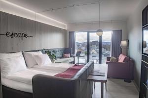 a bedroom with a large bed and a living room at Hotel Norge by Scandic in Bergen