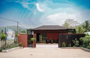 a red house with a gate and a motorcycle in front at H2cottage in Wodapatti