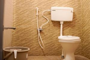 a bathroom with a toilet with a hose on the wall at H2cottage in Wodapatti