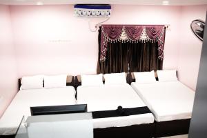 a room with three beds in front of a window at H2cottage in Wodapatti