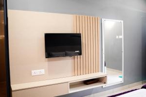 a flat screen tv on a wall with a mirror at H2cottage in Wodapatti