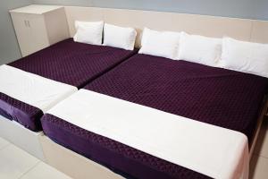 a bed with purple and white sheets and pillows at H2cottage in Wodapatti