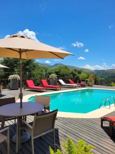 a swimming pool with a table and an umbrella at Espaço Tramonto in Itaipava