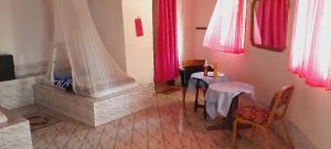 a living room with a fireplace and a table and chairs at WYCE Gambia Lodge in Dau Dula