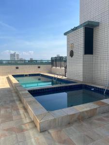 a swimming pool on the roof of a building at Aconchego no Canto do Forte - Ar Condicionados - Tvs Grandes - Wi-fi e Estacionamento Incluso! in Praia Grande
