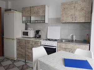 a kitchen with white appliances and a table with chairs at Apartament Azur in Călimăneşti