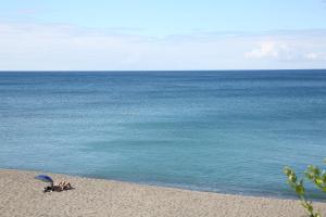 a person laying on a beach with an umbrella at Pestana Bahia Praia Nature & Beach Resort in Vila Franca do Campo