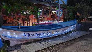 a blue boat sitting on a wooden deck with lights at Бунгало Шангри Ла-3, плаж Градина in Sozopol