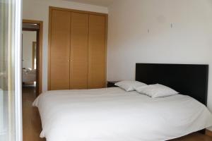 a bedroom with a white bed and a wooden closet at Vista Gama in Santa Iria da Azóia