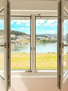 a room with two windows looking out at the water at Apartamento Saica by ALÔGA in Corcubión