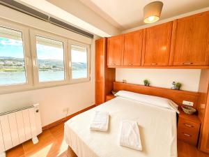 a bedroom with a bed and two windows at Apartamento Saica by ALÔGA in Corcubión
