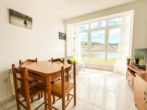 a dining room with a table and chairs and a window at Apartamento Saica by ALÔGA in Corcubión +6 photos