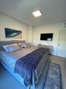 una camera da letto con un letto grande e una TV a schermo piatto di Casa em Resort Privado Alto Padrão a Capão da Canoa