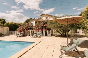 a patio with chairs and an umbrella next to a pool at Mas Saint-Ange in Lunel