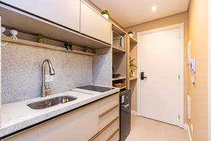 una piccola cucina con lavandino e porta di Studio Aconchegante com A/C no All Batel - BAT0821 a Curitiba