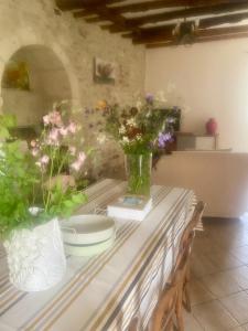 einen Tisch mit Blumen in Vasen darüber in der Unterkunft Les ambiances du Coly, La chambre Vézère in Condat-sur-Vézère