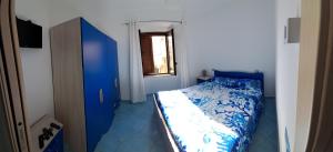a bedroom with a blue bed and a window at Monolocale centro!! in Palinuro